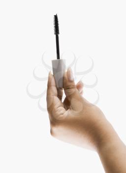 Close-up of a woman's hand holding a mascara brush