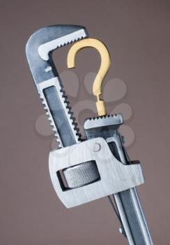Adjustable wrench crushing question mark symbol