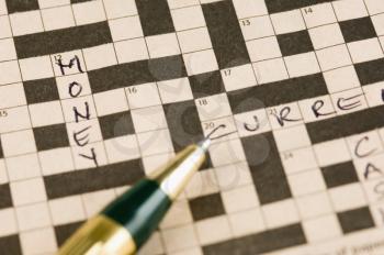 Close-up of a crossword puzzle with a pen