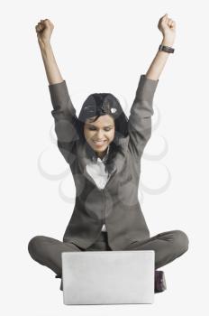 Woman smiling with her arms raised in front of a laptop
