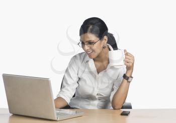 Businesswoman working on a laptop and drinking coffee