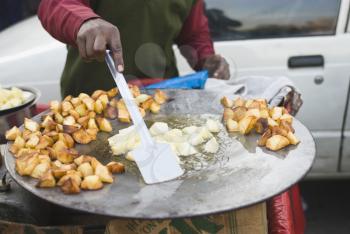 Man frying potato slices on a griddle, New Delhi, India