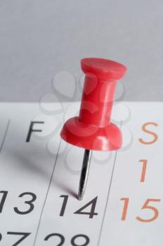 Close-up of a thumbtack on the 14th date of a calendar