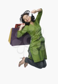 Young woman jumping with shopping bags and a credit card