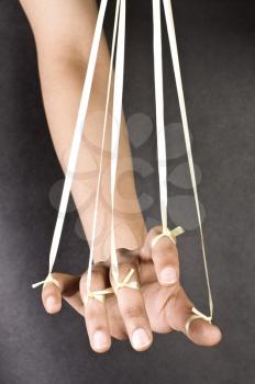 Close-up of a person's hand pulled by threads like a puppet