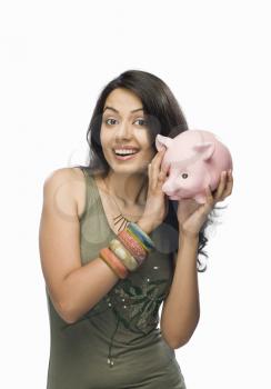 Portrait of a young woman shaking a piggy bank