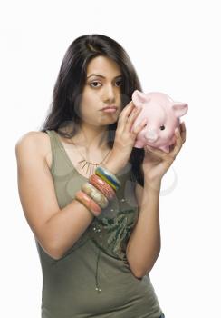 Portrait of a young woman worried with a piggy bank
