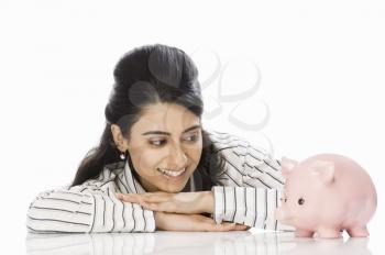 Businesswoman looking at a piggy bank