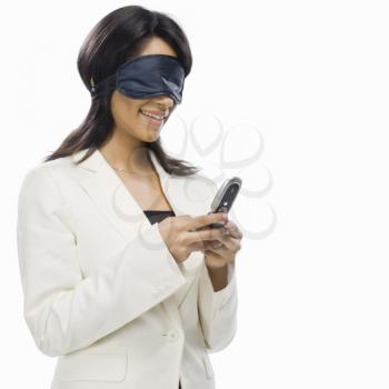 Businesswoman wearing eye mask and text messaging