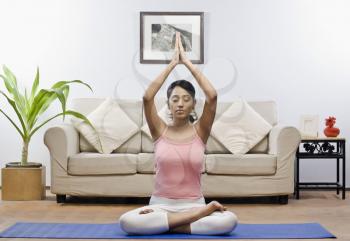 Young woman meditating in a living room