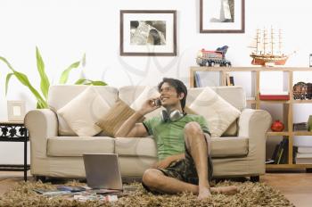 Young man talking on a mobile phone in the living room