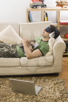 Young man lying on a couch and listening to music
