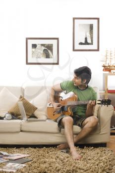 Young man playing a guitar in the living room
