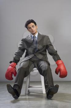 Bruised businessman wearing boxing gloves