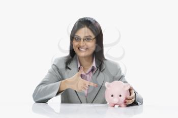 Businesswoman pointing at a piggy bank