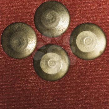 Close-up of four metallic push pins on a bulletin board