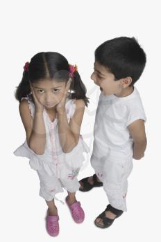 Girl covering her ears while her brother talking