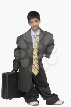 Portrait of a boy wearing oversized suit and holding briefcase
