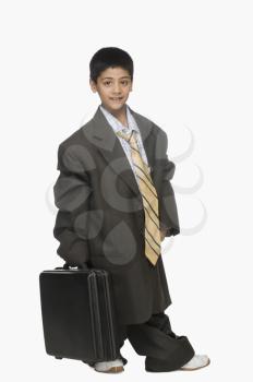 Portrait of a boy wearing oversized suit and holding briefcase