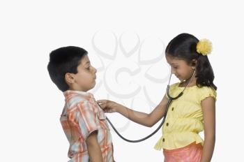 Side profile of a girl examining a boy with a stethoscope