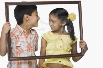 Boy and a girl holding an empty picture frame