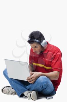 Man listening to headphones while using a laptop