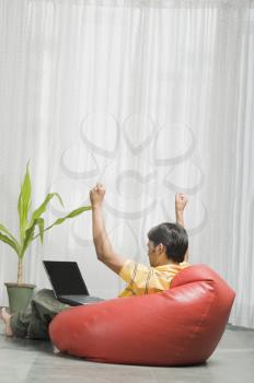 Young man sitting on a bean bag in front of a laptop