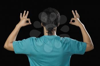 Rear view of a man gesturing OK sign