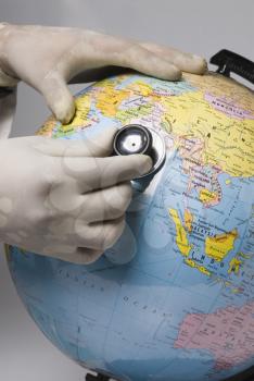 Close-up of a doctor's hand examining a globe with a stethoscope