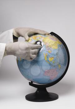 Close-up of a doctor's hand examining a globe with a stethoscope