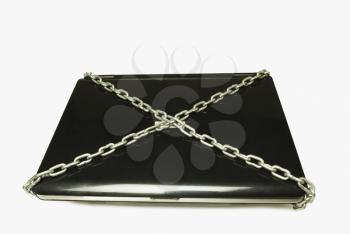 Close-up of a closed laptop tied with chains
