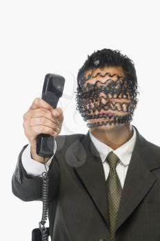 Businessman showing telephone receiver with his obscured face