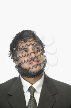 Close-up of a businessman's face covered with phone cord