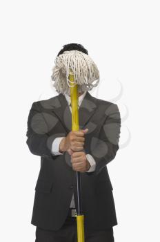 Businessman holding a broom in front of his face