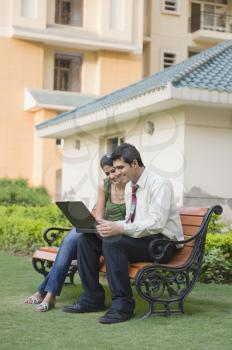 Couple sitting on the bench and using a laptop