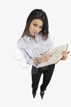 Portrait of a businesswoman marking on a book