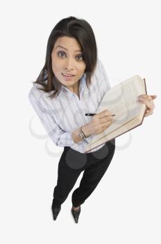 Portrait of a businesswoman marking on a book