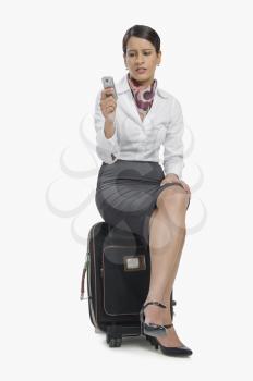 Air hostess sitting on her bag and text messaging on a mobile phone