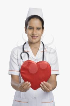 Female nurse holding a heart shape and smiling