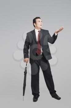 Businessman holding an umbrella and checking for rain