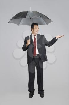 Businessman under an umbrella checking for rain