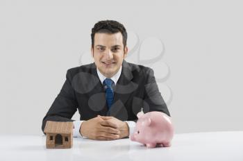 Businessman with a model home and a piggy bank
