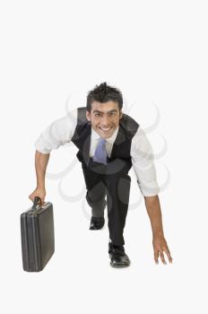 Businessman preparing for a race with a briefcase