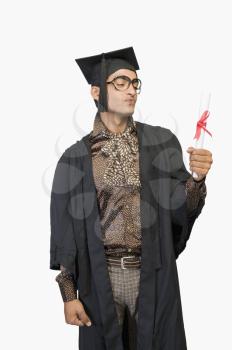 Man in a graduation gown holding a diploma