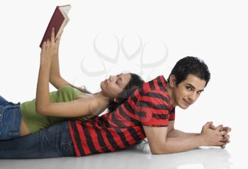 Woman lying on a man's back and reading a book