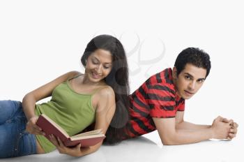 Woman leaning on a man's back and reading a book