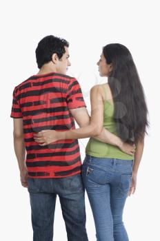 Rear view of a couple standing with arm around