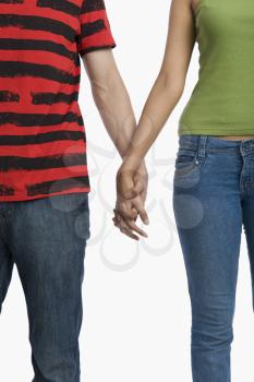 Mid section view of a couple holding hands