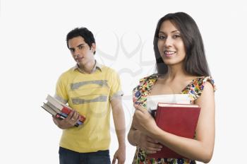 Woman holding books with boyfriend standing behind her