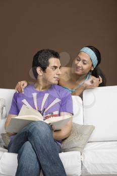Man holding a book and looking at his girlfriend